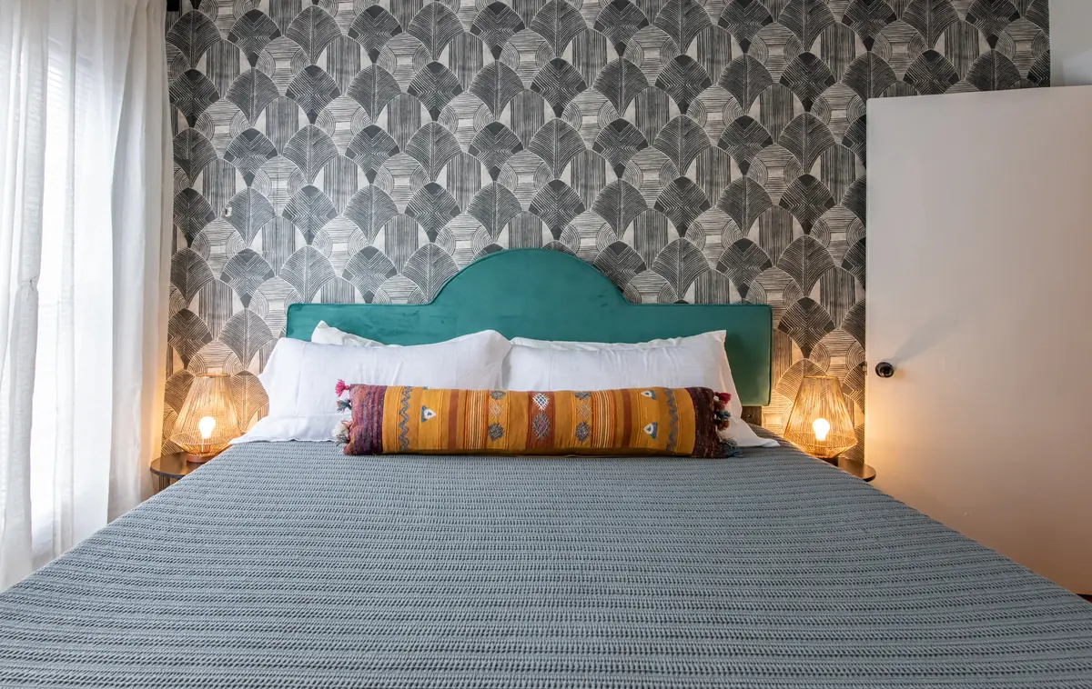 Unit A bedroom with a teal headboard and wallpaper